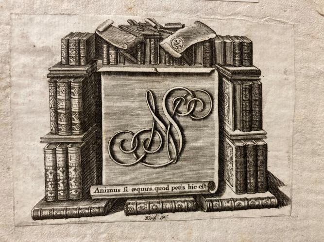 An etched image with initials shown surrounded by stacked books
