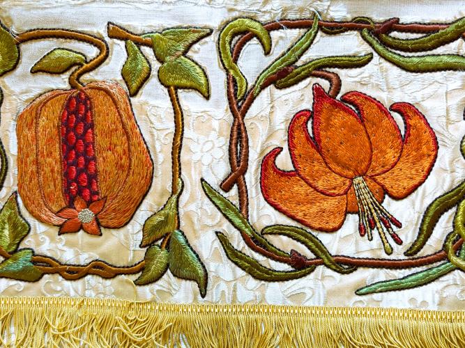 Detail of an embroidered cloth with a piece of fruit and flower 