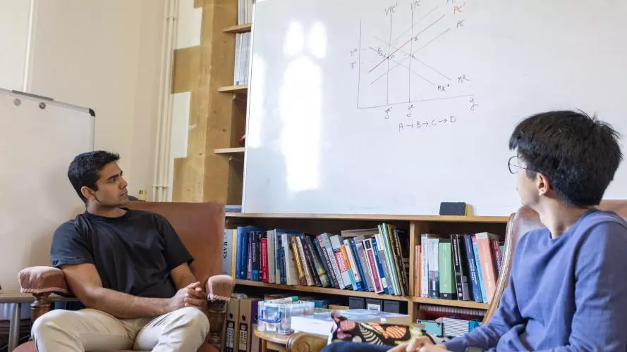 Two students in front of a whiteboard with a graph