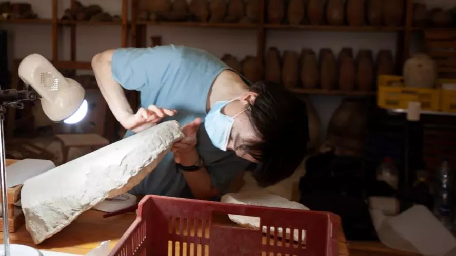 Hana Navratilova in a workshop inspecting an archaeological relic
