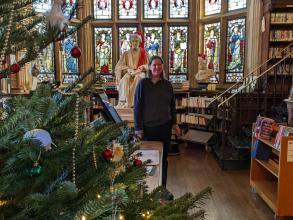 A photograph with a Christmas tree in the foreground, then a staff member, followed by the stained glass windows.