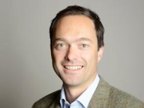 Professor Jan-Emmanuel de Neve, former Vice-Principal of HMC, posing in front of a grey background.