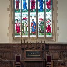 View down the centre of the Chapel with stained glass shown above an altar table 