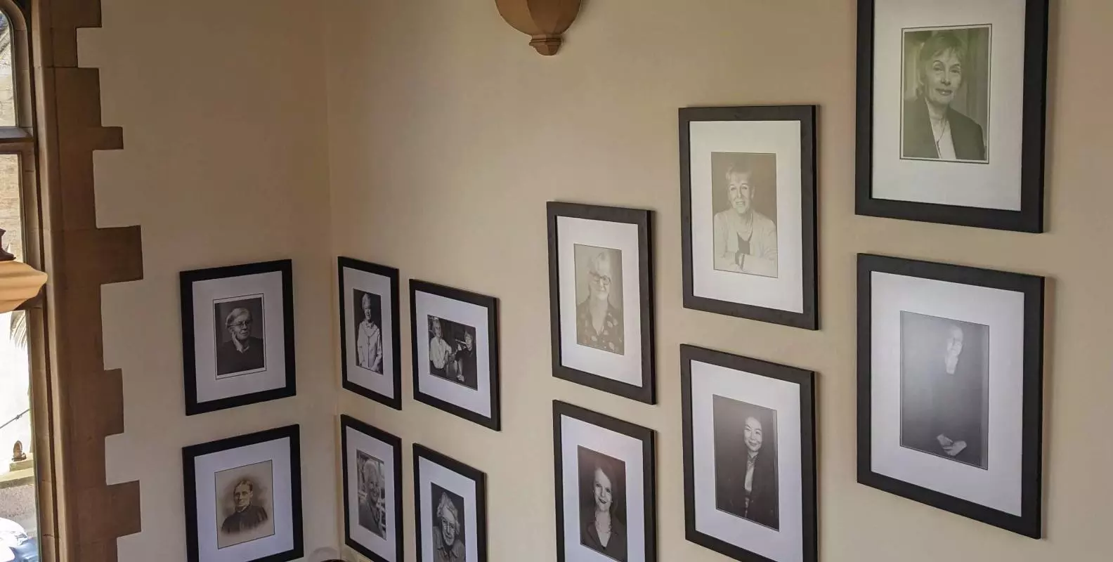 A closer view of the Women Who Made (Harris) Manchester College portraits, mounted on the wall. 