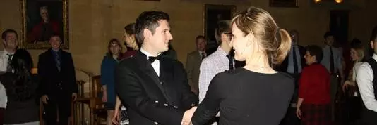A group of people wearing Scottish tartans and dancing inside of Arlosh Hall.