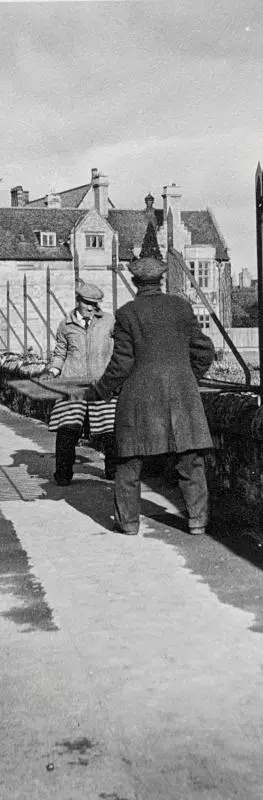 Two men moving a large metal railing from a wall