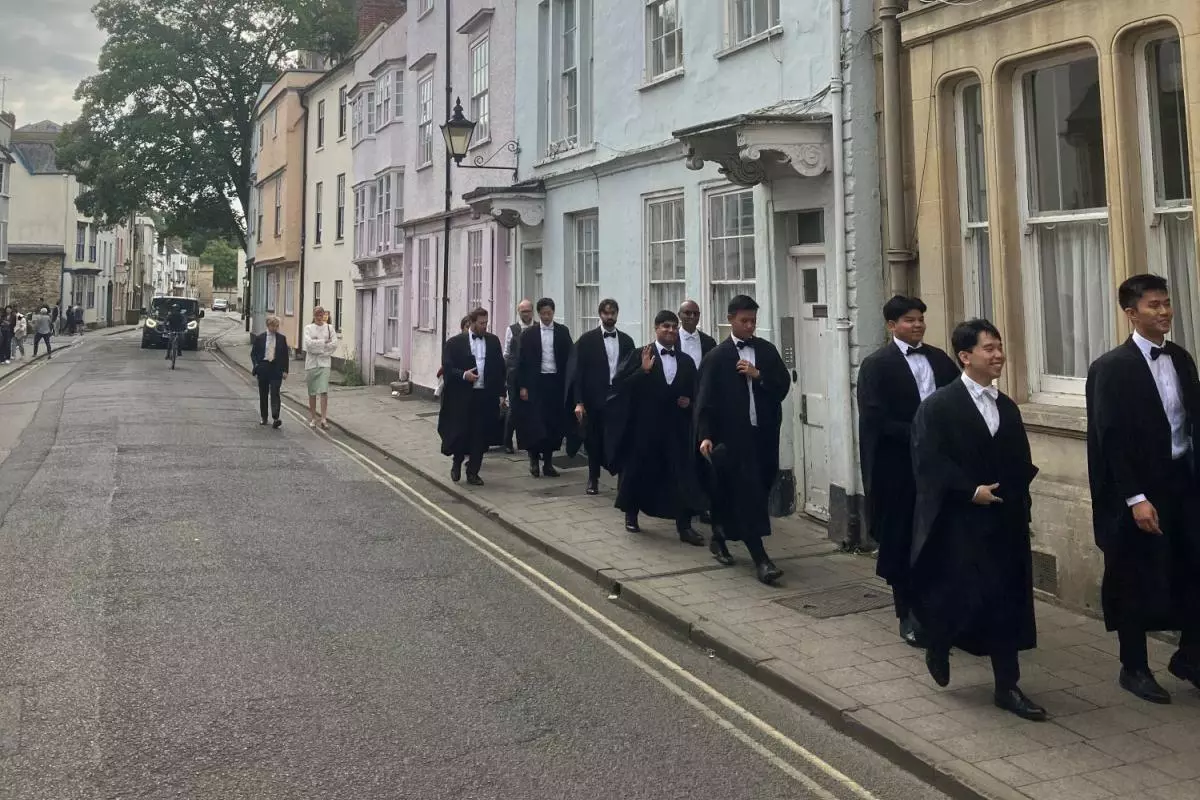 Students in gowns walking down Holywell Street, Oxford