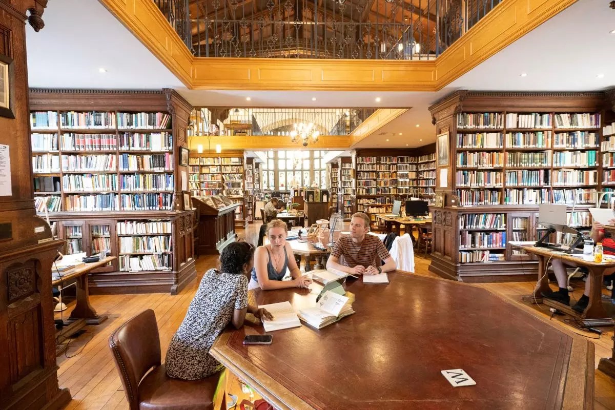 Three students seated around a table in a library